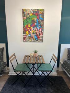 伦敦Willesden Green ROOMS的一张桌子和两把椅子,墙上挂着一幅画