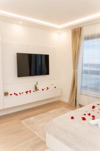 贝尔格莱德SINFONIA LUX的一间配有电视的白色客厅和床上的红色玫瑰
