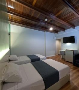 加拉加斯Hotel El Arroyo的酒店客房设有两张床和电视。