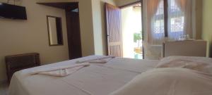 乌巴图巴Suítes Jardim dos Sonhos的一间卧室配有一张带白色床单的床和一扇窗户。