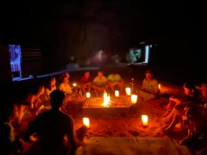 瓦迪拉姆Bedouin Memories Camp的一群人坐在火炉边,拿着蜡烛