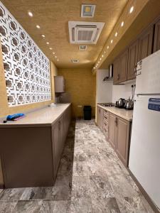 Al Khabrāʼشاليه غرناطة的配有白色冰箱和橱柜的大厨房