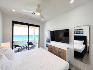 西湾Luxury Ocean front SeaDreams 2 with 7 Mile Beach Views的一间卧室配有一张床和一台平面电视
