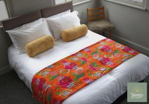 沃辛Sleep Hotel的床上有色彩缤纷的毯子和枕头