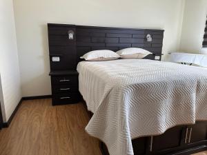 科恰班巴Departamento Ebano Apt 1E的一间卧室配有一张大床和黑色床头板