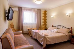 HaysynГотель Гайсин «Тіроль»的一间卧室配有一张床、一张沙发和一台电视。