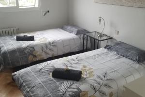 马德里Casa de Mirtha的一间卧室配有两张床和一张带台灯的桌子