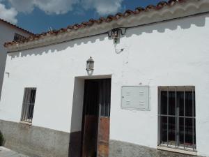 塞维利亚La casita en la Alcornocosa -Sevilla的白色的建筑,有门和街灯