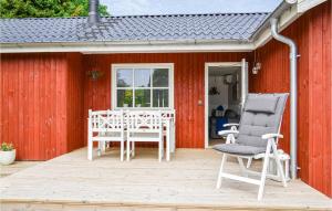 埃贝尔托夫特Cozy Home In Ebeltoft With Wifi的红色的房子,配有带椅子和桌子的甲板