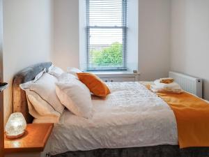 福克兰Invergyle - Uk40566的一张带橙色和白色枕头的床和窗户