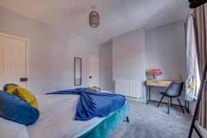 卡斯尔福德Liquorice Lodge- 2 bed & parking的一间卧室配有一张带蓝色床单的床和一张书桌。