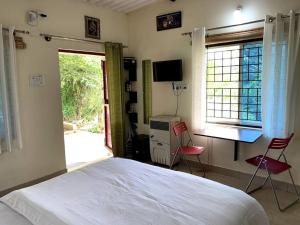 班加罗尔Sattva Farmstay的一间卧室配有一张床、一张桌子和两把椅子