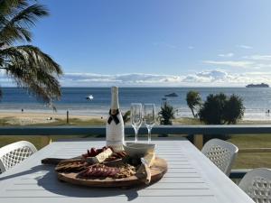天阁露玛Paradise Palms Tangalooma的一张桌子,上面有一瓶葡萄酒和眼镜,放在沙滩上