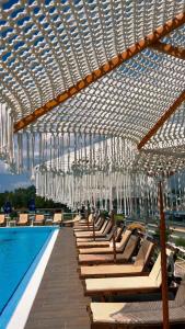 地拉那Misk Hotel & Resort的游泳池畔设有椅子和吊灯