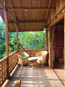 武吉拉旺Rambai Tree Jungle Lodges的一个带藤椅和桌子的门廊