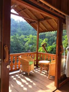 武吉拉旺Rambai Tree Jungle Lodges的木制门廊配有桌椅