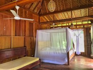 武吉拉旺Rambai Tree Jungle Lodges的客房设有一张床和一个吊扇。