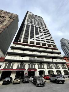 吉隆坡M101 KLCC KL city King Suites by Livin的一座高大的建筑,前面有汽车停放