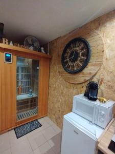 滨海贝尔克Gîte Sauna Balnéo Berck sur Mer Lâchez Prise的厨房配有墙上的时钟和冰箱