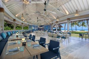 鲁阿环礁Ifuru Island Resort Maldives - 24-Hours Premium All-inclusive with Free Domestic Transfer的餐厅设有桌椅,背景为大海