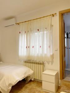 阿尔考本达斯Pensión el Carmen的一间卧室配有床和白色窗帘的窗户