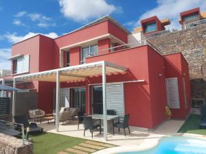 马斯帕洛马斯Villa Vista Golf Salobre - Maspalomas self-sufficient with pool heating的红色的房子,设有庭院和游泳池