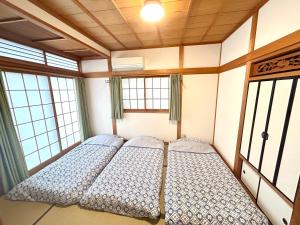 高松浜町小院别馆的带2扇窗户的客房内的2张床
