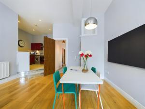 贝尔法斯特Fitzrovia Mansion Apartments in Belfast's Cathedral Quarter的一间配备有白色桌子和蓝色椅子的用餐室