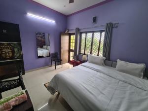 阿格拉安努科姆帕宾馆的一间卧室设有紫色的墙壁和一张大床