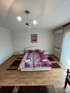 ŽiviniceApartmani Hadžić的一间卧室配有一张带粉红色棉被的床