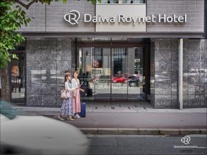 京都京都四条乌丸大和ROYNET酒店的两名妇女站在一座建筑物前面