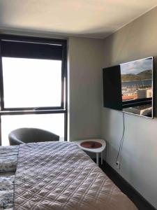 波多Rom m/bad i Bodø sentrum的卧室配有一张床,墙上配有电视。