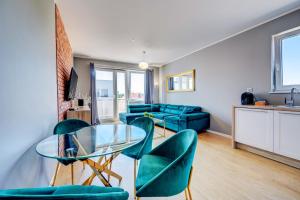 什切青Allure Nautica Aparthotel的客厅配有玻璃桌和绿色椅子