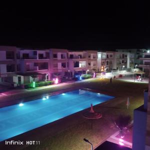 曼苏里亚Málaga beach el mansouria的一座夜间游泳池,其建筑背景为: