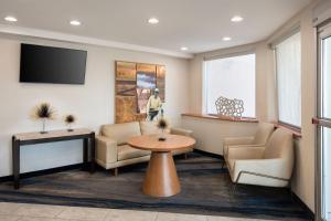 皇后区纽约拉瓜迪亚机场/芙拉世迎费尔菲尔德万豪酒店的一间设有椅子和桌子的等候室以及一台电视
