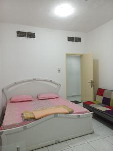 沙迦Holiday Home 2 Bedrooms Apartment for Family Only的一间卧室配有一张带粉红色床单和椅子的床