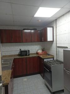 沙迦Holiday Home 2 Bedrooms Apartment for Family Only的厨房配有木制橱柜和炉灶烤箱。