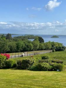 戈尔韦Hillcrest Lodge, Private apartment on Lough Corrib, Oughterard的水景带围栏的田野