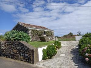 拉日什Rosário Guest House的石头房子,有石墙和草地