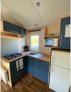 BoofzheimMobile home proche de Europa Park的厨房配有蓝色橱柜、水槽和冰箱。