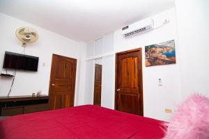曼塔Habitaciones privadas, Casa de Amber, Manta的一间卧室配有红色的床和一台平面电视