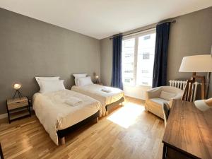 勒芒La Villa Maignan - Centre ville - Jardin - 15p的一间卧室设有两张床、一把椅子和一个窗户。