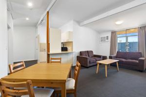 阿德莱德Econo Lodge East Adelaide的客厅设有餐桌和沙发