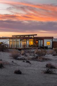 约书亚树Panoramic Heaven - Luxury Designer Property w Spa的沙漠中的一座建筑,背景是日落