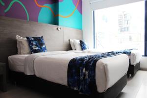 波哥大Agora Suites Self-Service Boutique Hotel的一间卧室设有两张床和彩色的墙壁