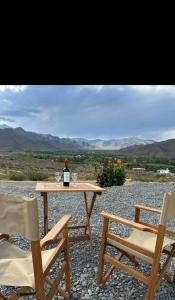 卡奇Cabaña Abra Del Monte的一张桌子、一瓶葡萄酒和两把椅子