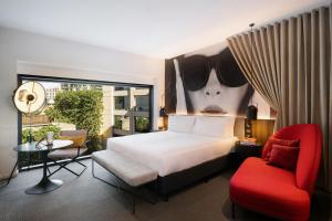 墨尔本Hotel Indigo Melbourne on Flinders, an IHG Hotel的一间卧室配有一张床和一张红色椅子