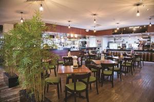玛丽伯勒运营阿尔姆斯酒店汽车旅馆的餐厅设有木桌和绿色椅子