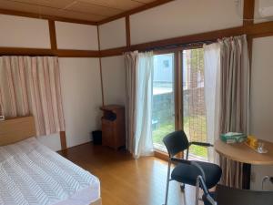 筑紫野市民泊　筑紫野的一间卧室配有一张床、一张书桌和一个窗户。