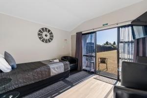陶波Central Inn Taupo的一间卧室设有一张床和一个滑动玻璃门